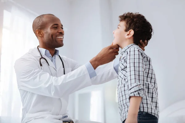 Merry glad male doctor checking boys throat — Stock Photo, Image