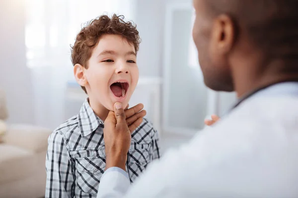 可爱的男孩显示喉咙对男性医生 — 图库照片