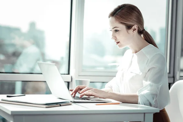 Koncentrerad upptagen kvinna sitter och använder den bärbara datorn. — Stockfoto