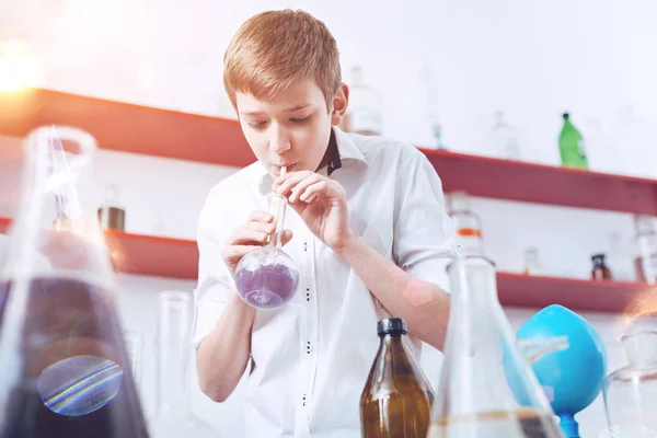 Nastoletnich chemik dmuchanie w kolbie w laboratorium szkoły — Zdjęcie stockowe