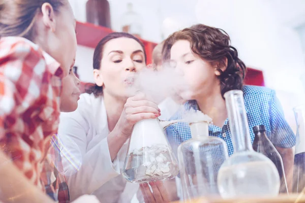 Tutor de química y estudiantes de primaria soplando en el humo en el laboratorio —  Fotos de Stock