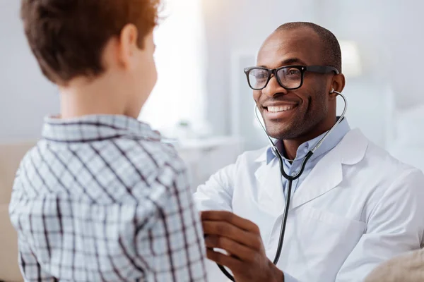 Afro american male doctor examining boys respiratory system — Stock Photo, Image