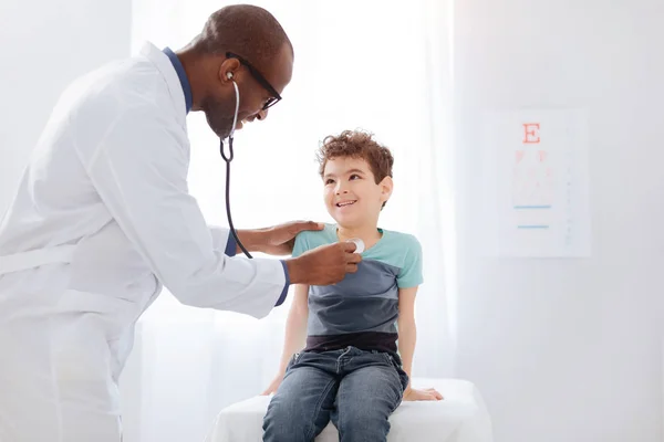 Positive male doctor checking boys health state — Stock Photo, Image