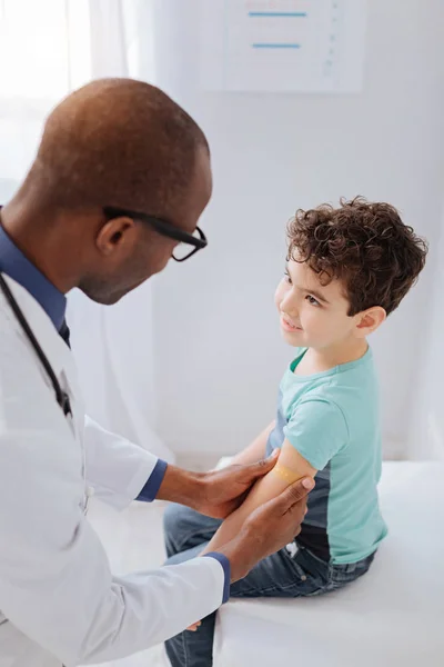 Afroamericano médico masculino presionando parche en la mano — Foto de Stock