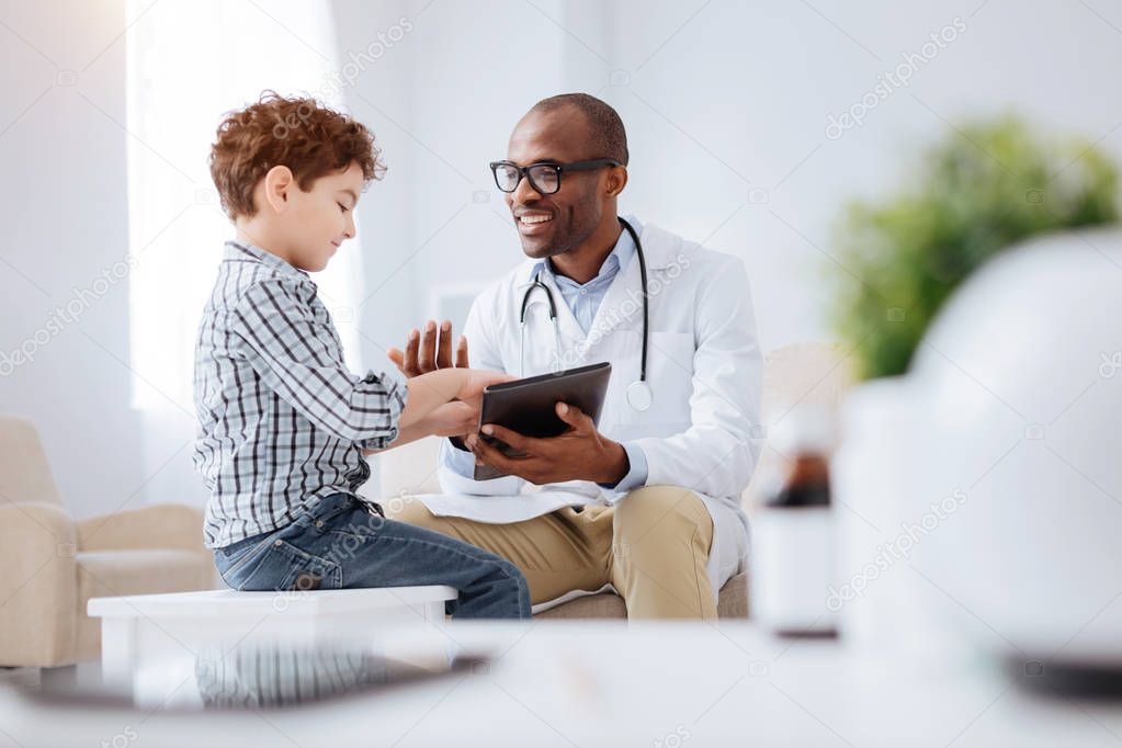 Optimistic male doctor sharing his work with boy