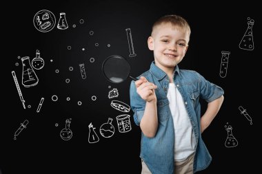 Büyüteç ile ayakta ve mutlu bir şekilde gülümseyerek neşeli çocuk