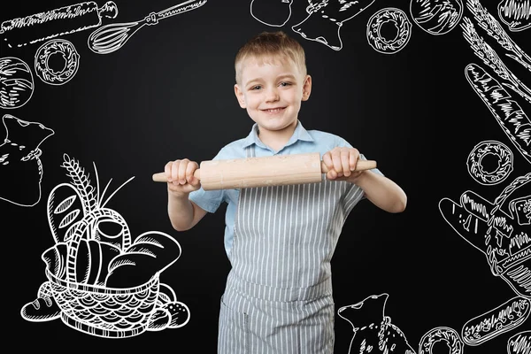 Bambino positivo che tiene un mattarello e sembra pronto per iniziare a cucinare — Foto Stock