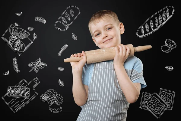 Carino bambino sorridente allegramente mentre in piedi con un mattarello — Foto Stock