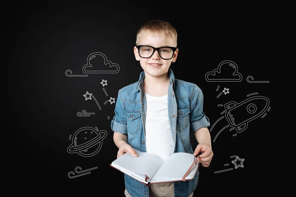 Lachende jongen houdt van een notebook en dromen over het reizen naar de ruimte — Stockfoto