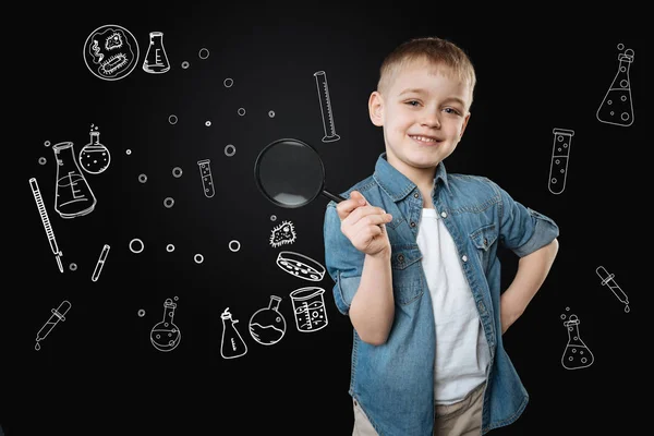 Fröhlicher Junge, der mit einer Lupe steht und glücklich lächelt — Stockfoto