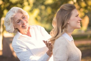 Smiling old woman expressing love to the daughter outdoors clipart