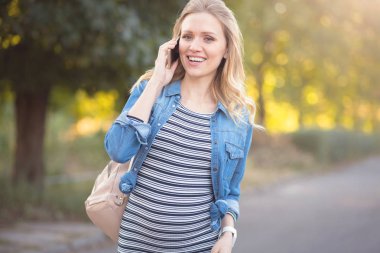 Telefonunuzun ve açık havada büyüleyici hamile kadın