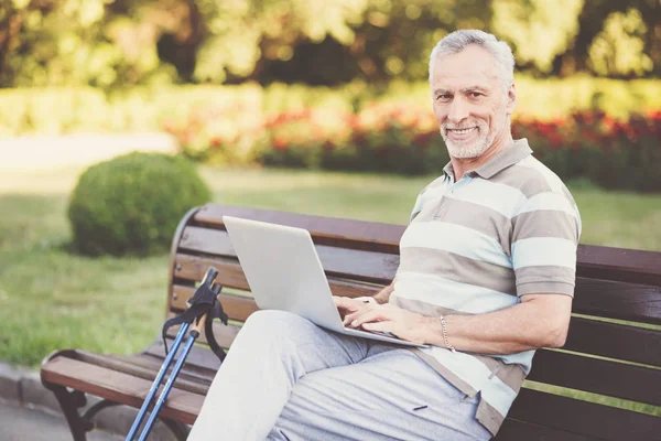 Веселый пожилой человек, работающий над ноутбуком — стоковое фото
