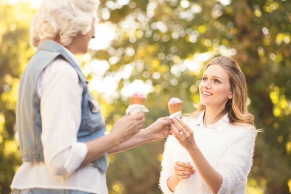 Mujer joven divertida degustación de helado con la madre anciana al aire libre —  Fotos de Stock