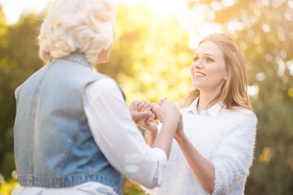 Kind woman holding hands with grandmother in the park — Stock Photo, Image