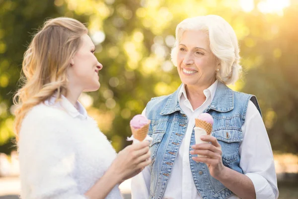 Молодая женщина наслаждается мороженым со стареющей матерью на открытом воздухе — стоковое фото