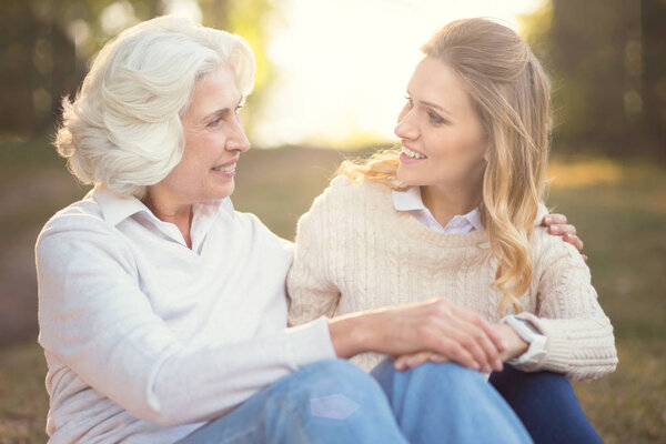 Caring woman having conversation with elderly mother in the park