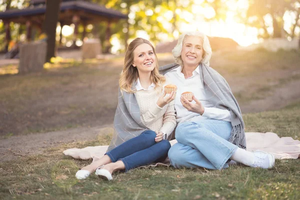 Happy woman eating dessert with old mother at the picnic — Stock Photo, Image