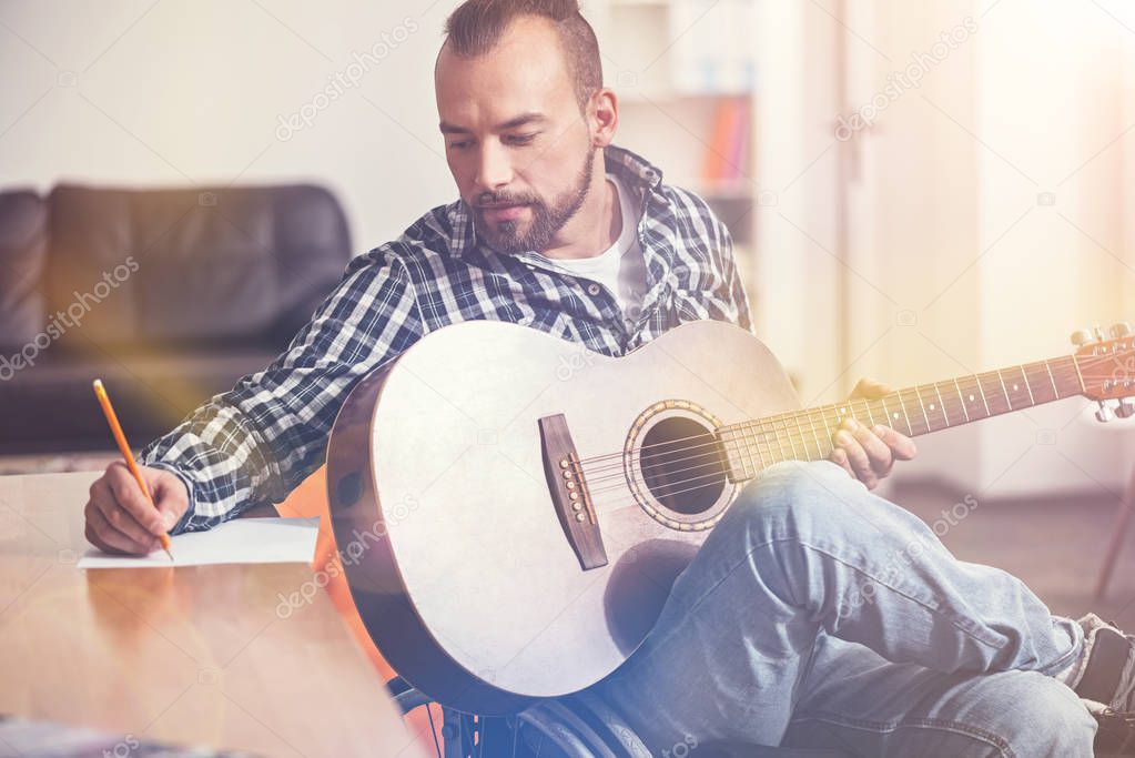 Serious bearded man looking at his writing hand