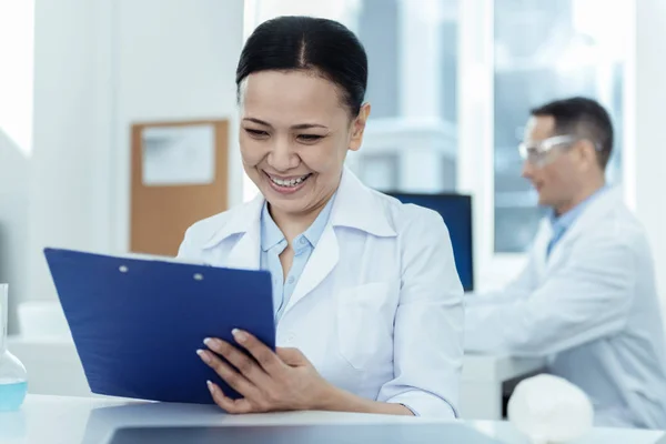 Cientista sorridente toma nota dos resultados — Fotografia de Stock