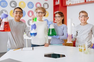 Grup neşeli öğrenci laboratuarında kimyasal şişeler ile poz