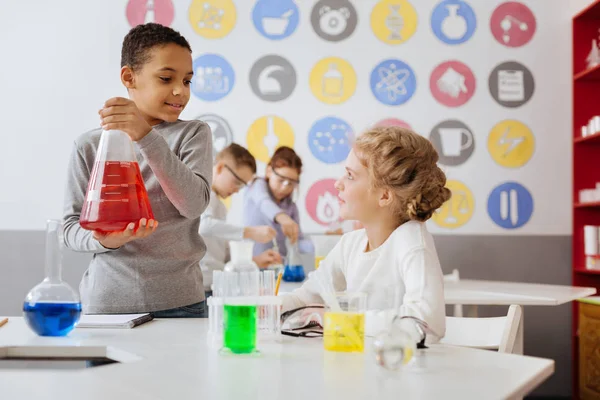 Agréable garçon parlant avec son partenaire d'équipe pendant les cours de chimie — Photo