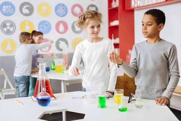 Upbeat schoolchildren looking at pipette with chemical — Stock Photo, Image