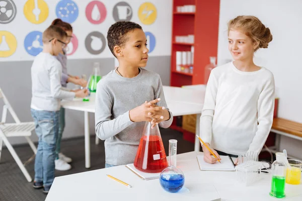 Pleasant schoolchildren thinking about chemistry project — Stock Photo, Image
