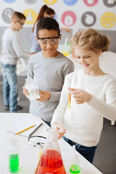 Cheerful boy watching his classmate conduct chemical experiment — Stock Photo, Image