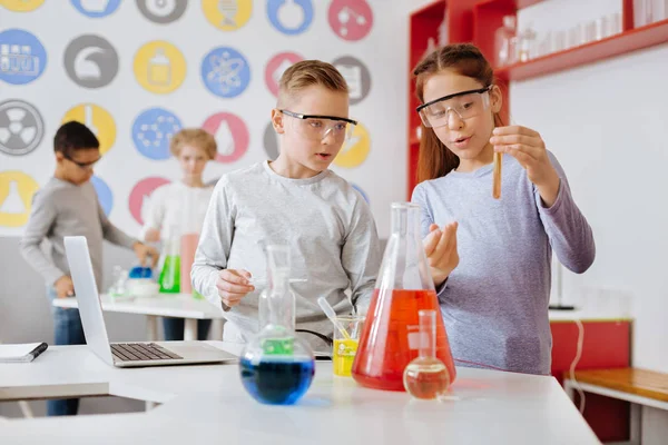 Estudantes agradáveis examinando tubo de ensaio com produto químico — Fotografia de Stock