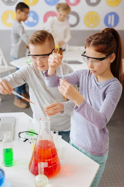 Diligent classmates adding chemicals to sample tubes — Stock Photo, Image