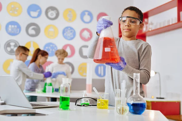 Charming boy observando la reacción química en el frasco — Foto de Stock