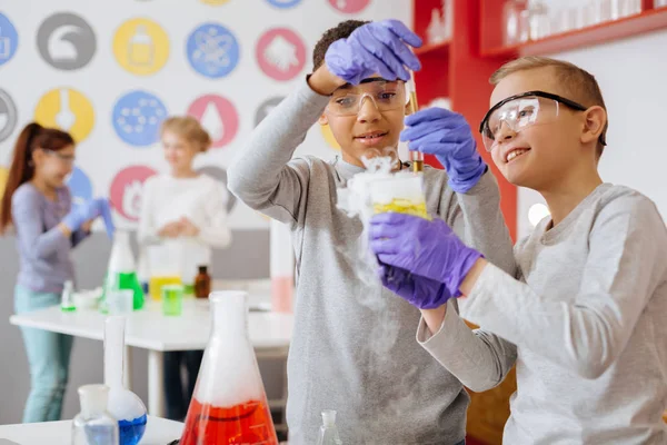 Gladlynt pojke visar hans vän kemisk reaktion under klass — Stockfoto