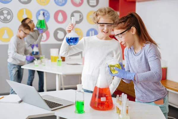 Meninas alegres verificando a correção da reação química — Fotografia de Stock