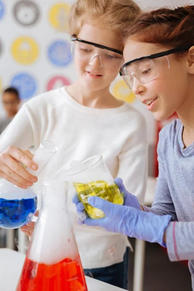 Cheerful girls mixing chemicals in a big flask — Stock Photo, Image