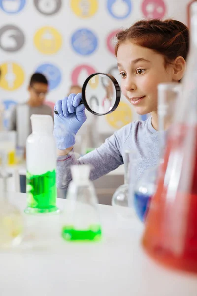 Estudante bonito observando reação química através de lupa — Fotografia de Stock