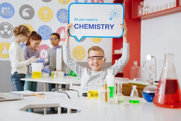 Cheerful boy holding All You Need is Chemistry board
