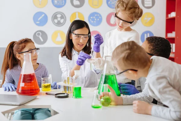 Trevlig kemilärare hjälper sina elever genomföra experiment — Stockfoto