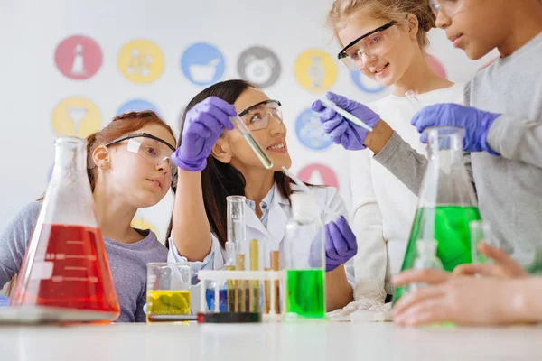 Encantadora maestra mostrando a sus estudiantes tubo con agente químico — Foto de Stock