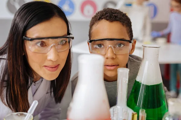 Professora alegre e sua aluna observando reação química — Fotografia de Stock