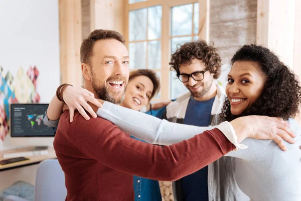 Alegres trabajadores sonriendo y abrazándose — Foto de Stock