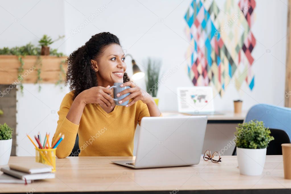 Alert freelancer smiling and drinking tea