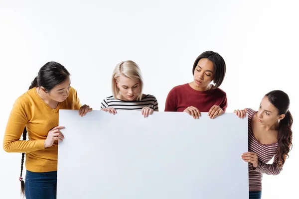 Inteligentes mujeres agradables mirando el cartel — Foto de Stock