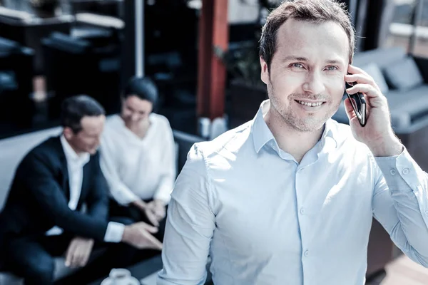 Delighted good looking man holding his smartphone — Stock Photo, Image