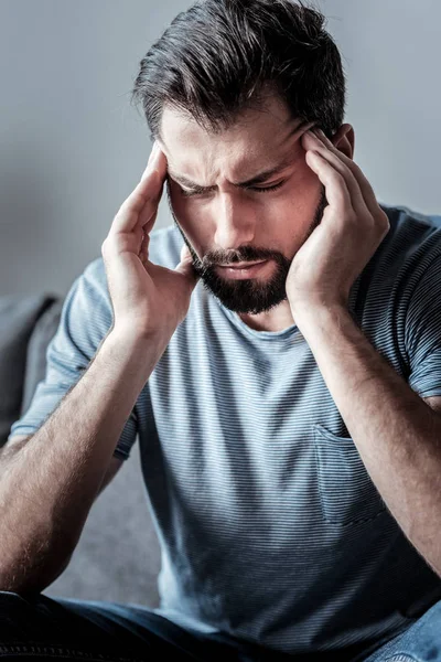 Sad young man holding his temples — Stock Photo, Image