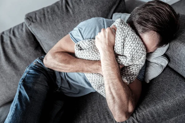 Cheerless sad man crying in the cushion — Stock Photo, Image