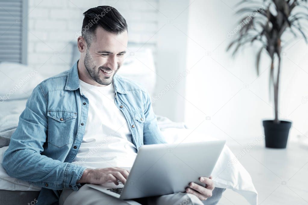 Cheerful positive man looking at the laptop screen