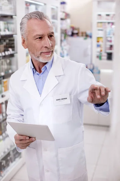 Focused male pharmacist correcting data