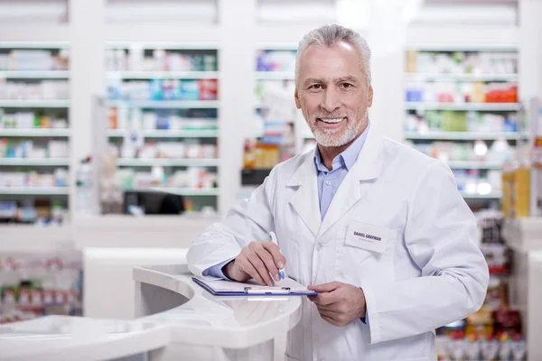 Pozytywne mężczyzna farmaceuty, wypełniając formularz — Zdjęcie stockowe