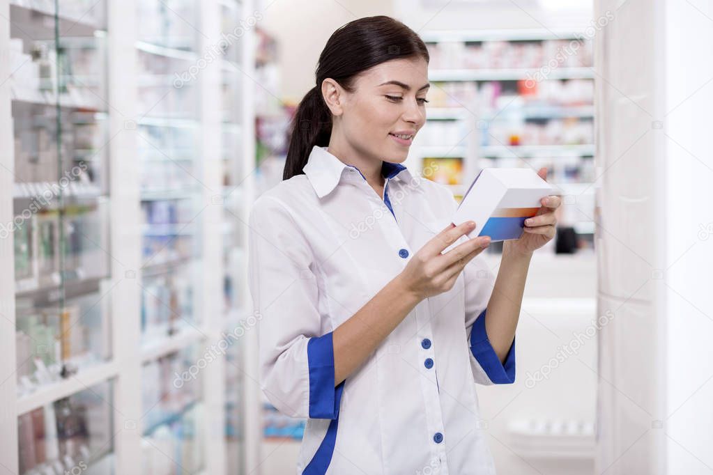 Reflective female pharmacist supervising production